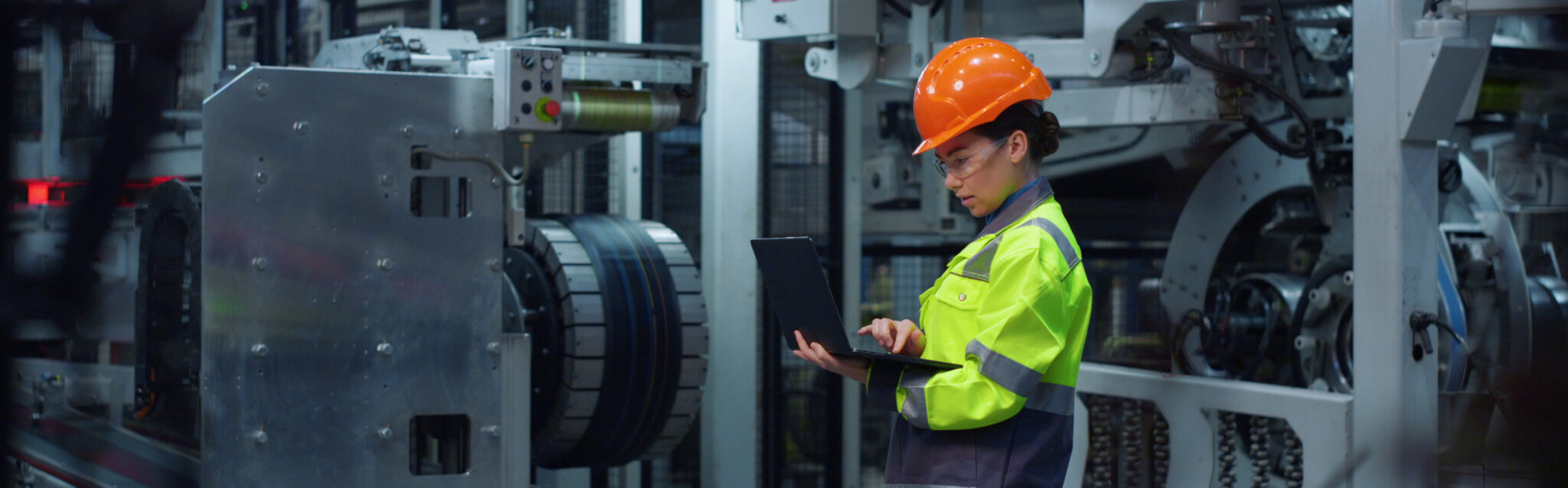 Woman engineer using CEDOC on a laptop computer wearing safety uniform on factory. Focused industrial professional holding modern laptop computer. Serious specialist working digital project at facility.